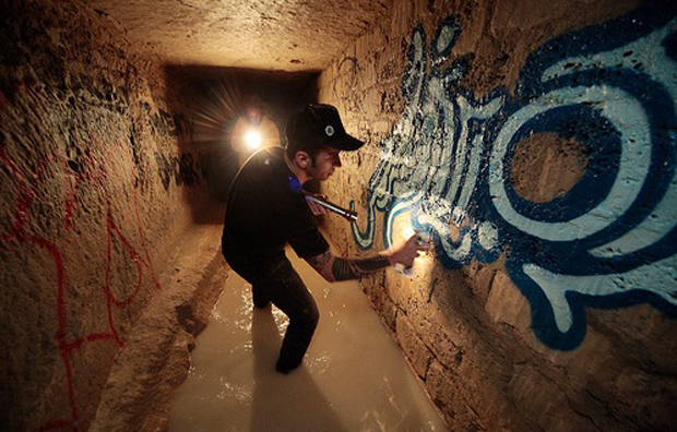 O artista brasileiro Zezão grafitando uma das paredes da galeria subterrânea